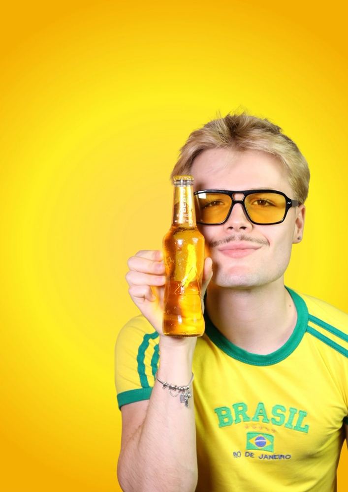Modelo con una botella de Beats Tropical y remera de Brasil, fondo amarillo